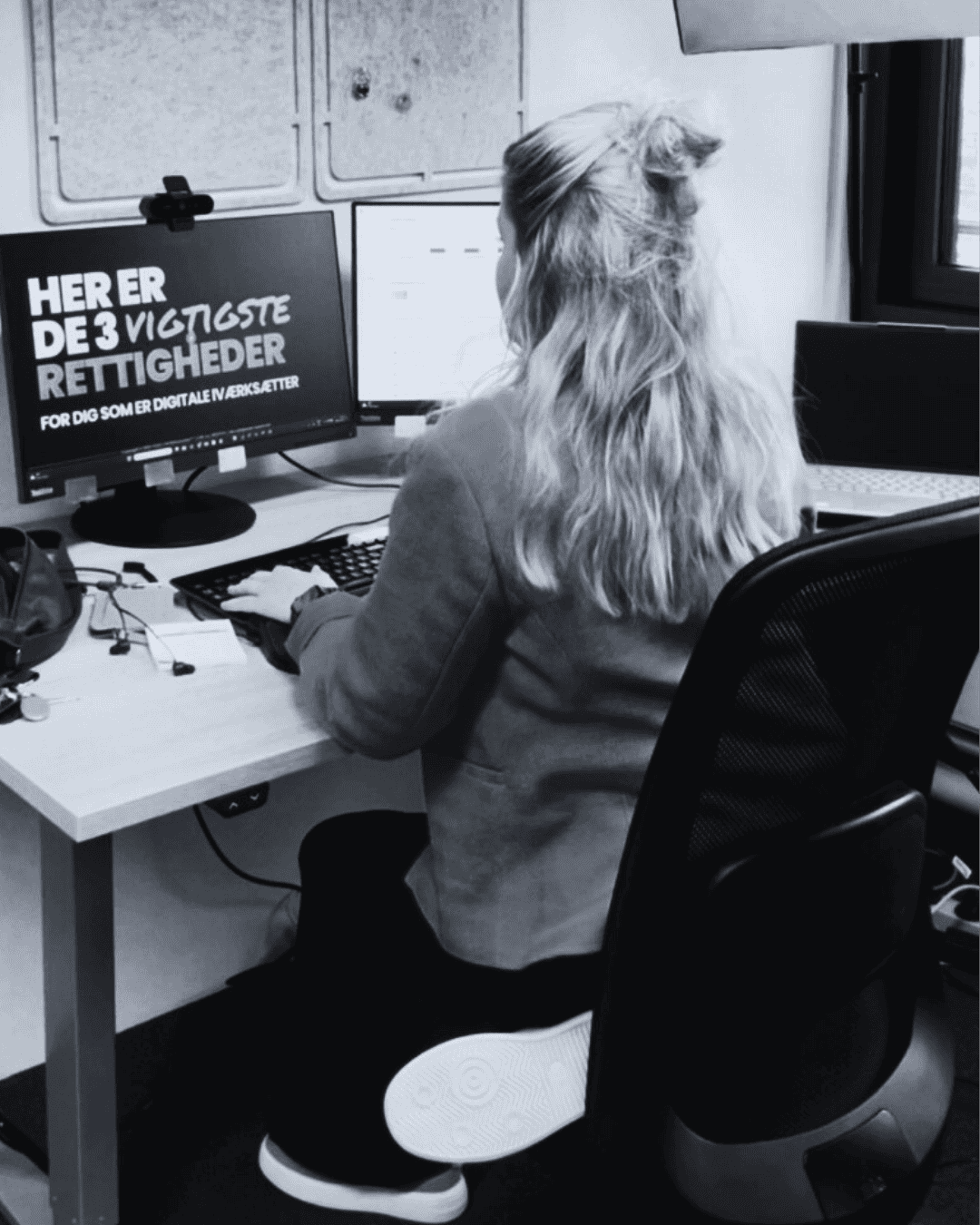 A person with long hair sits at a desk, meticulously formulating an ip strategy on a computer. The monitor displays text in a foreign language, reflecting the office's international reach.